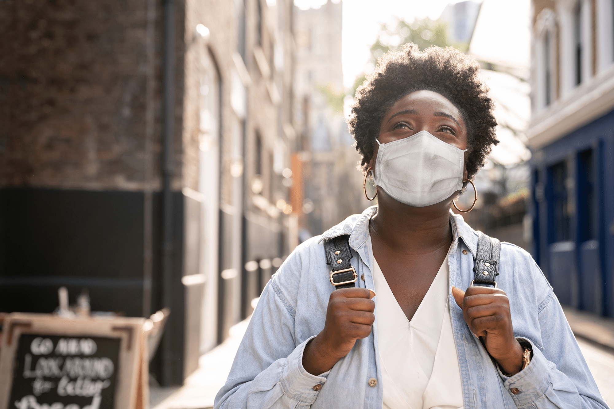 Thoughtful black woman wearing a facemask on the street